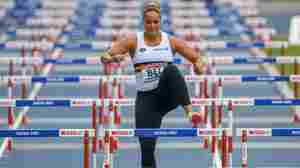 A Belgian shot-putter hops over hurdles after answering her team's call for help